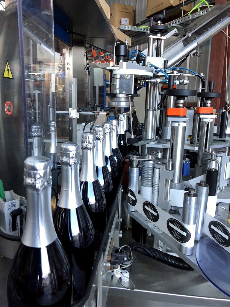 Sparkling wine bottles moving through the bottling and labelling line.