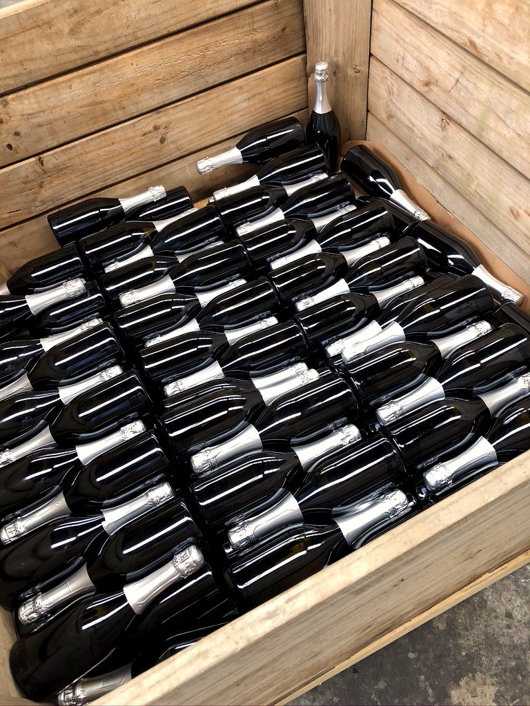 Finished sparkling wine bottles packed in a timber crate.
